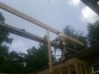 Carpenter setting a ridge beam over a new addition frame — Ice Dam Removal by Roofing Brothers in Fort Meade