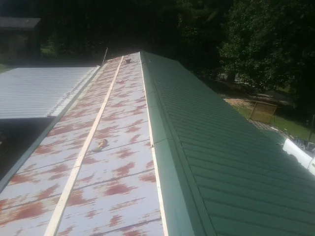 Old rusted panels beside newly installed green metal roofing — Wind Damage Roof Repair by Roofing Brothers in Fort Meade