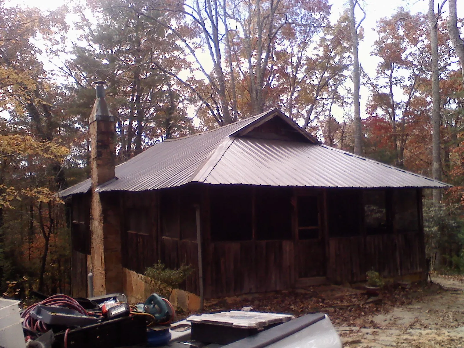 Brown metal hip roof on an old cabin with a stone chimney in Fort Meade