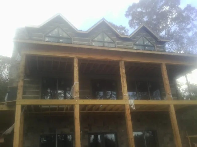 Dormers and porch framing on a large log home under construction — Roof Coating work by our crew in Fort Meade