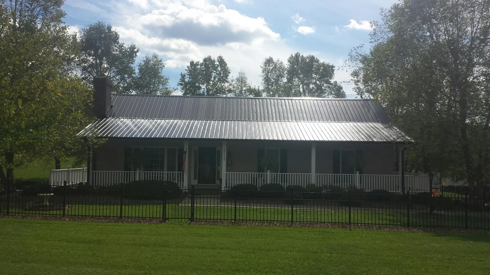 Gray metal roof on a brick ranch with a full width front porch — Gutter Guard Installation work by our crew in Fort Meade