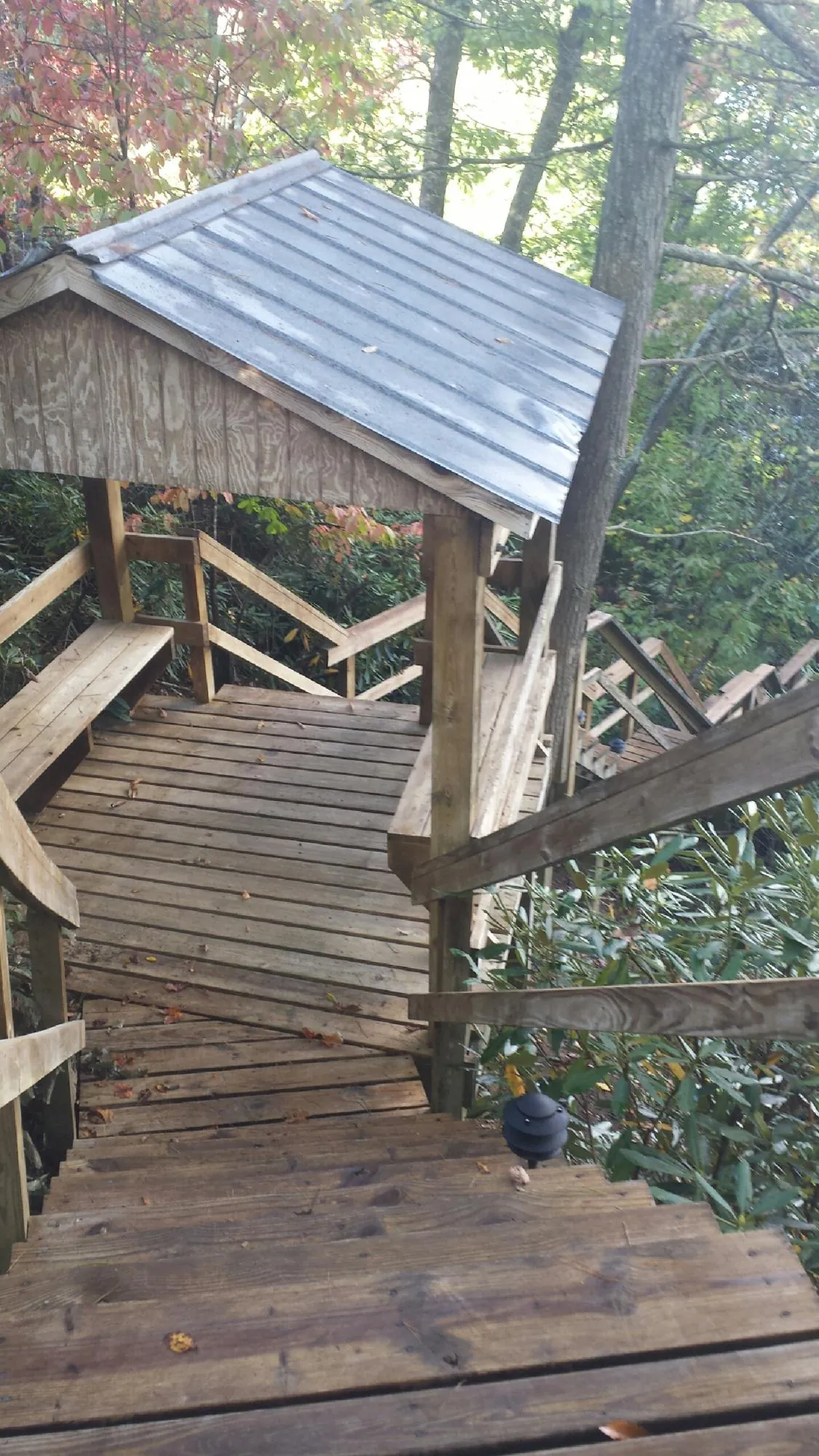 Metal roofed shelter over wooden steps on a wooded walkway — Skylight Repair & Installation work by our crew in Fort Meade