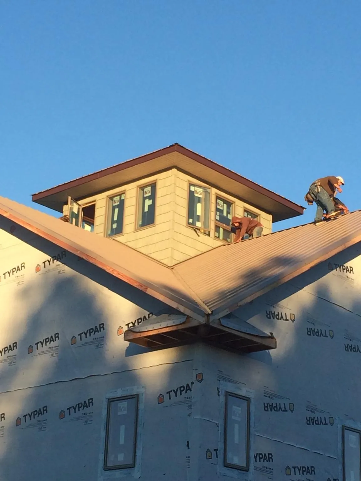 Roofers working around a rooftop cupola on a new metal roof at sunset — Roof Waterproofing in Fort Meade by Roofing Brothers